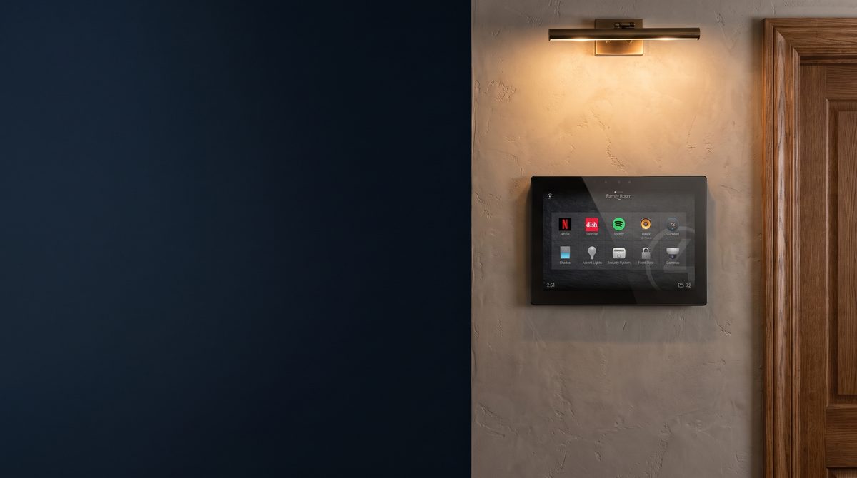 A Control4 touchscreen glowing on a hallway wall