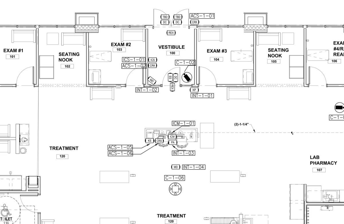 Detail from a real security plan sheet: exam rooms and vestibule with access control, door contact, request-to-exit, keypad, intercom and camera device tags, each keyed back to the riser