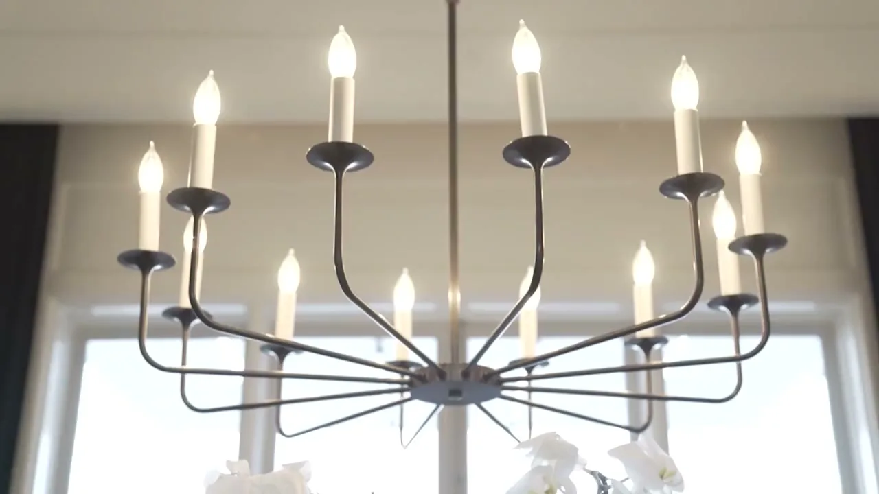 Quiet rooms of a luxury home: a chandelier in daylight, drapes against a window, a vaulted white hallway